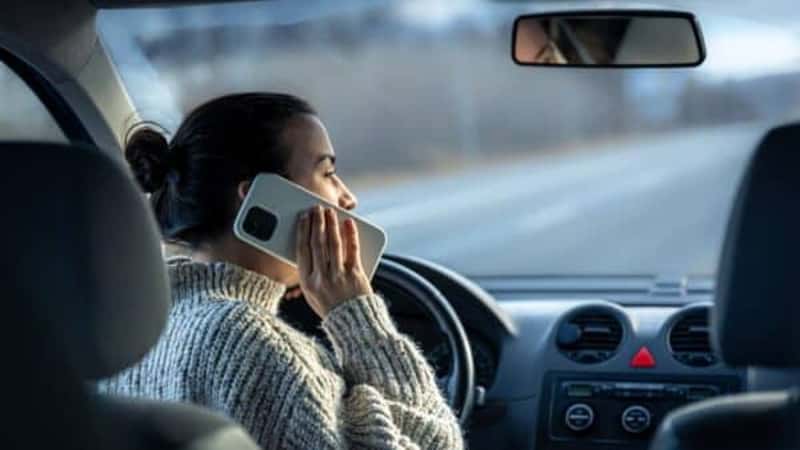 Young woman talking on the phone while driving a car.