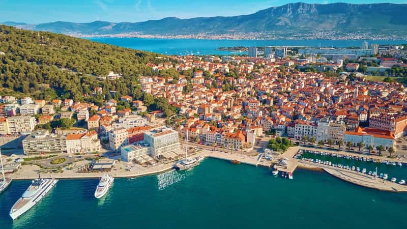 Aerial view of Split, Croatia. Cityscape of coastal touristic city with harbor with mountains in background. Old town with historical red roof tiled buildings near Adriatic Sea