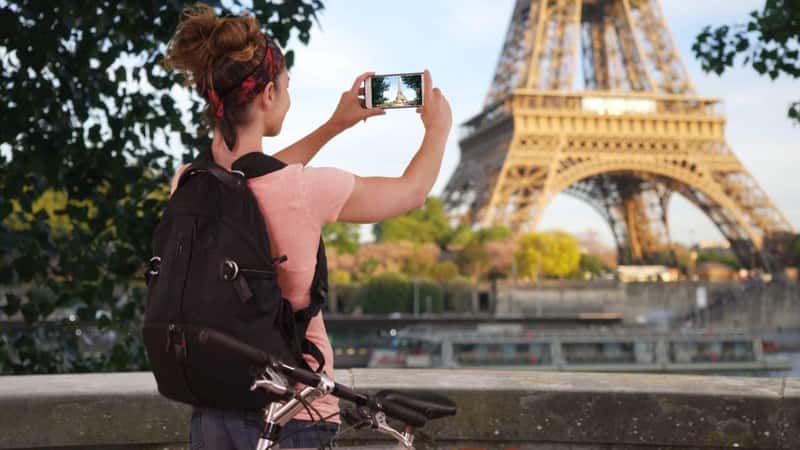 Young fit Caucasian woman bicyclist taking video of Eiffel Tower on phone