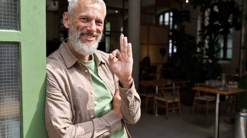 Happy older middle aged man small local business owner showing ok hand sign standing outside cafe or bar giving recommendation or feedback, suggesting good quality welcoming clients. Portrait