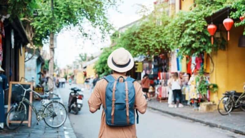 happy Solo traveler sightseeing at Hoi An ancient town in central Vietnam, man traveling with backpack and hat. landmark and popular for tourist attractions. Vietnam and Southeast Asia travel concept