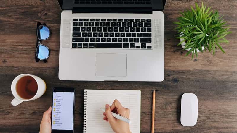 Woman writing travel packing checklist when getting getting ready for summer vacation