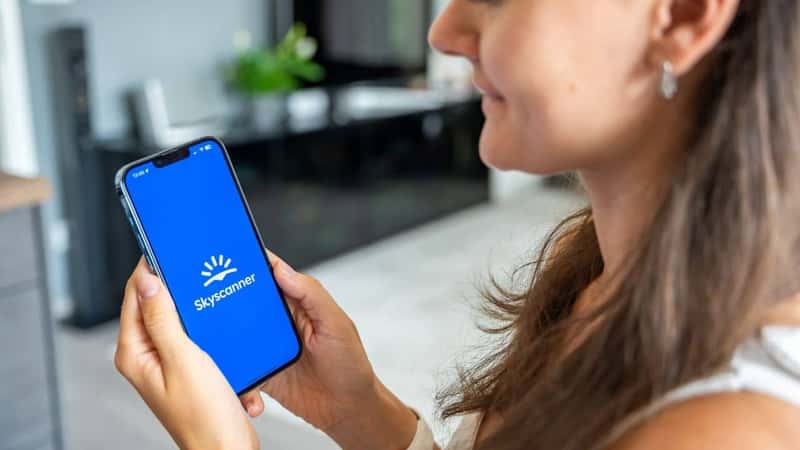 Prague, Czech republic - May 2, 2024: Woman holding iPhone with logo of application Skyscanner on the screen, using mobile application . High quality photo