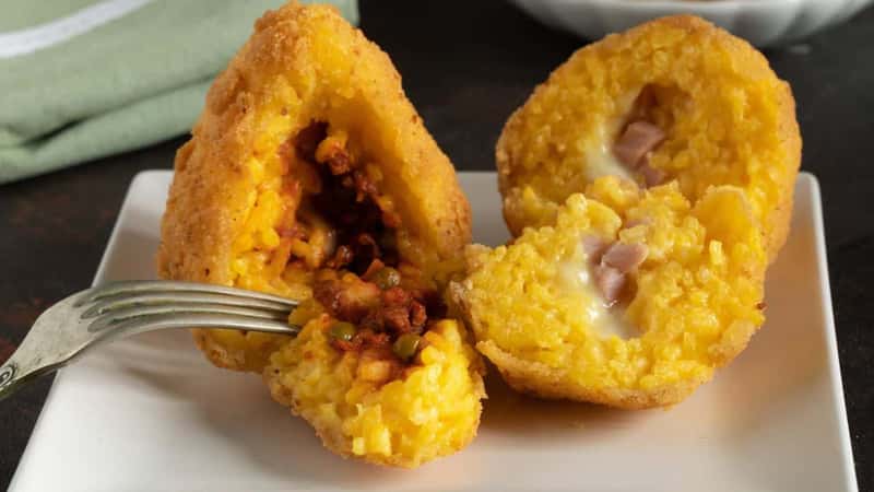 Arancini detail, traditional Italian food, mostly Sicilian, one stuffed with meat and peas ragu and another, so-called butter, stuffed with ham and mozzarella cheese.