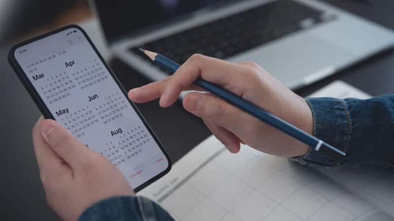 2023 Calendar event planner timetable agenda plan on organize schedule. Business woman using mobile phone with monthly calendar for event planning, Plan scheduling with laptop on office table