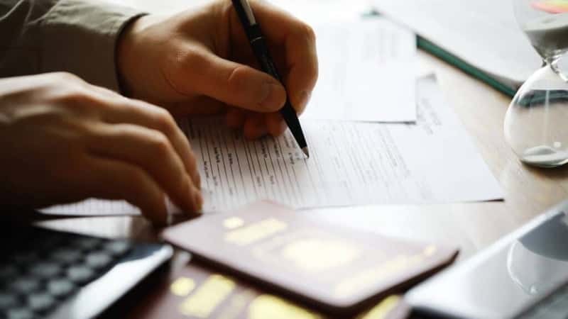Filling Out Forms for International Travel with Passports, Papers, and Pen on Desk