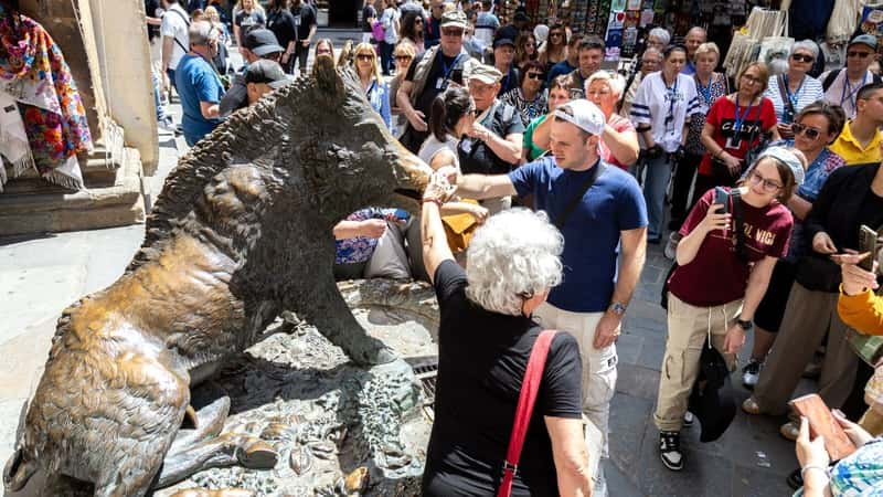 Florence, Italy - May 10th, 2025: Tourists gather around Il Porcellino statue, taking part in the tradition of touching the boar snout for good luck