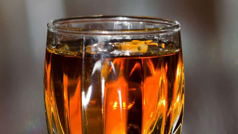 closeup of a shot glass full of bourbon served on a bar top