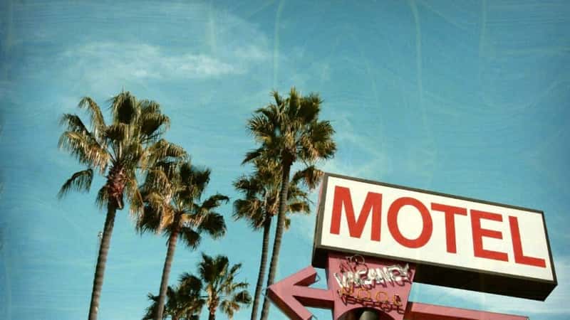 aged and worn vintage photo of motel sign palm trees
