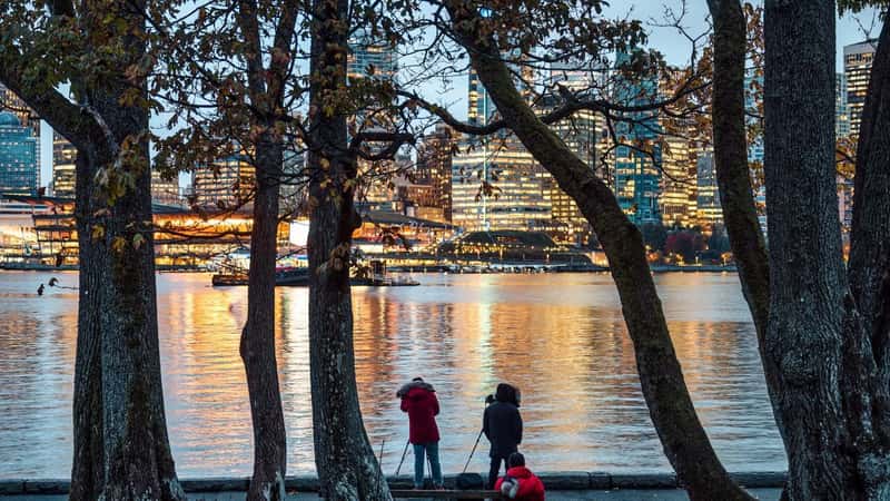 Group of photographer taking a photo with cityscape of illuminated building from Stanley Park in the evening at Vancouver, Canada