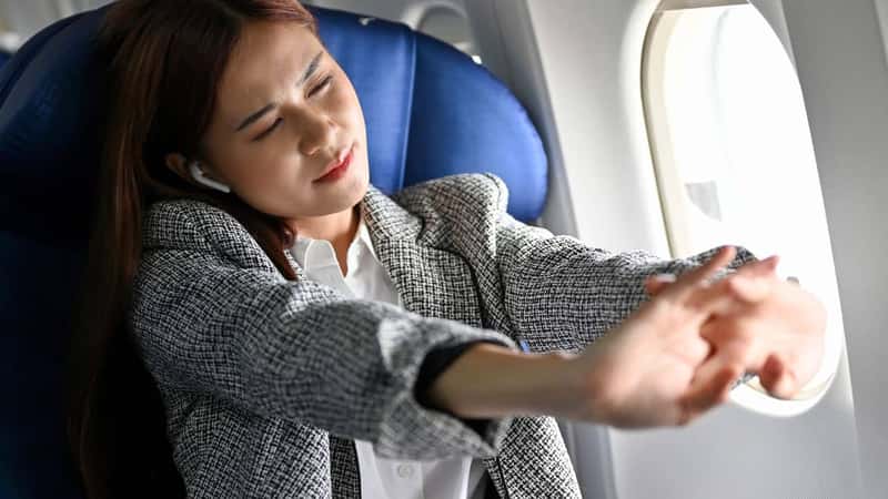 Beautiful asian young businesswoman stretching arms, feeling uncomfortable and tired during a long flight flying to another country. Business trip concept