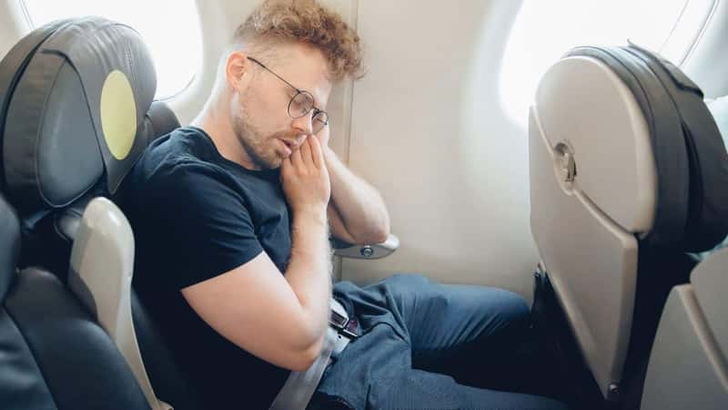 Concept traveling by plane. Young man traveler passenger sleeping in airplane.