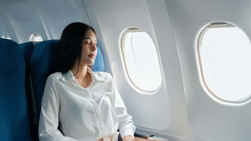 A female passenger traveling by plane sleeping on cushion airplane