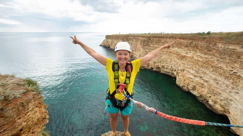 Young woman jump from the cliff with a rope. Ropejumping