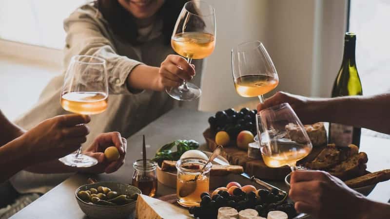 Glasses of white orange or rose wine in peoples hands