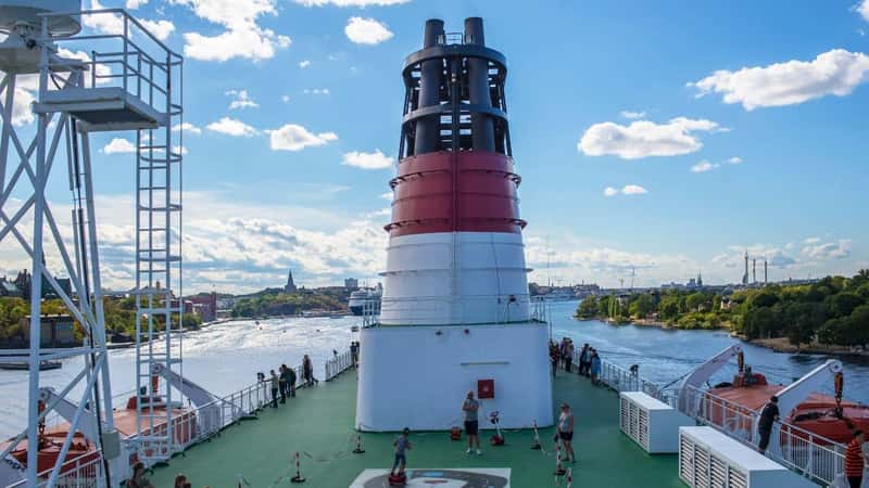 Sweden, Stockholm, 8/7/2018, Cruiser, upper deck, people walk and watch the city panorama, smoke stack. Boy drill driving.