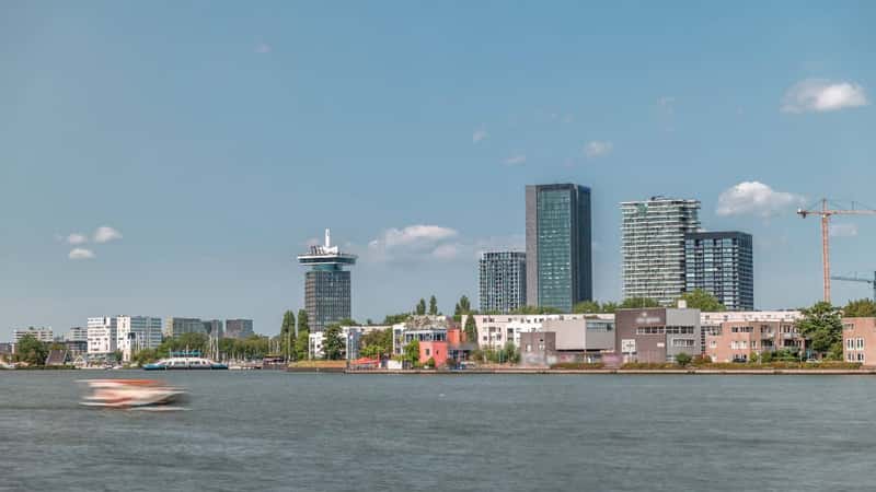 Timelapse panorama of the most fashionable modern towers in Amsterdam, located in the city center on the Hey embankment near the Eye Film Museum. A ferry crosses river under a blue sky. Netherlands