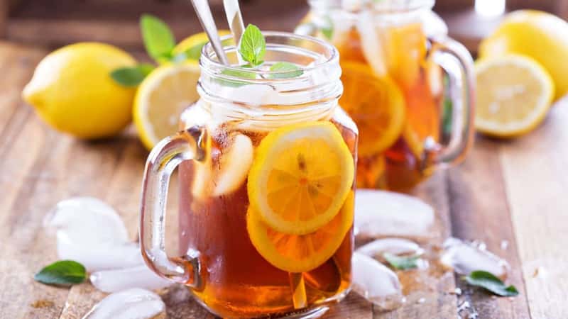 Iced tea with lemon slices and mint on rustic background