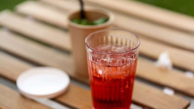 Closeup of glass with drink standing on desk outdoors cafe. Relaxation concept, refreshing drink, alcohol cocktail, selective focus 
