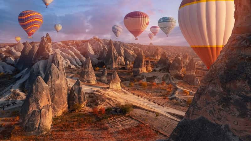 Group horse riding tour with hot air balloons in Cappadocia autumn landscape Turkey top aerial view.