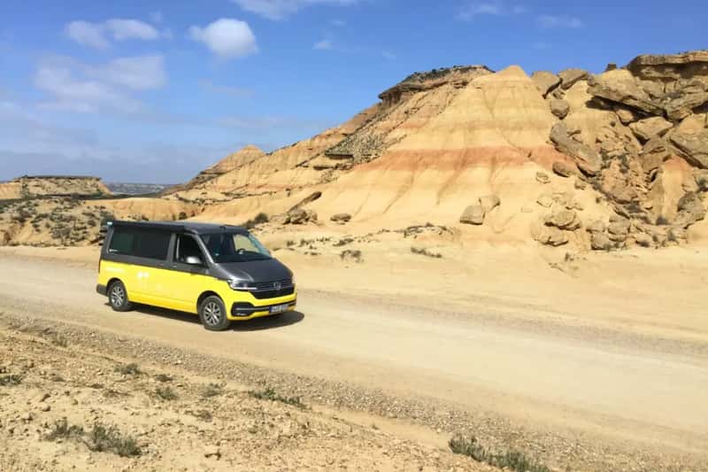yellow van in the desert of bardenas reales close to a little hill