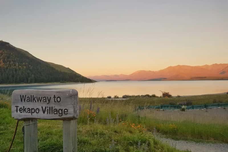 picture of the lake tekapo during sunset and the signage of the tekapo village