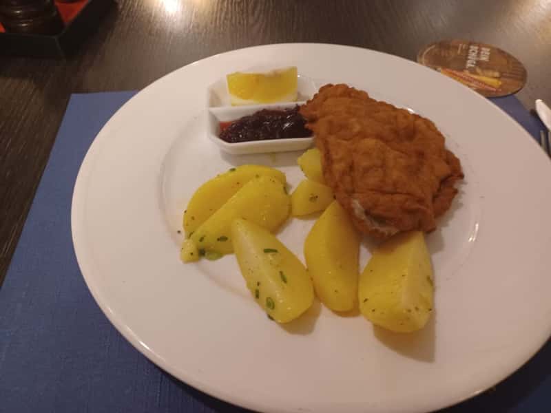 a weiner schnitzel with fried potatoes on a white plate at restaurant engels vaduz lichtenstein