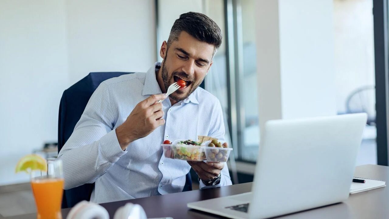Man enjoying a healthy lunch at his desk while working